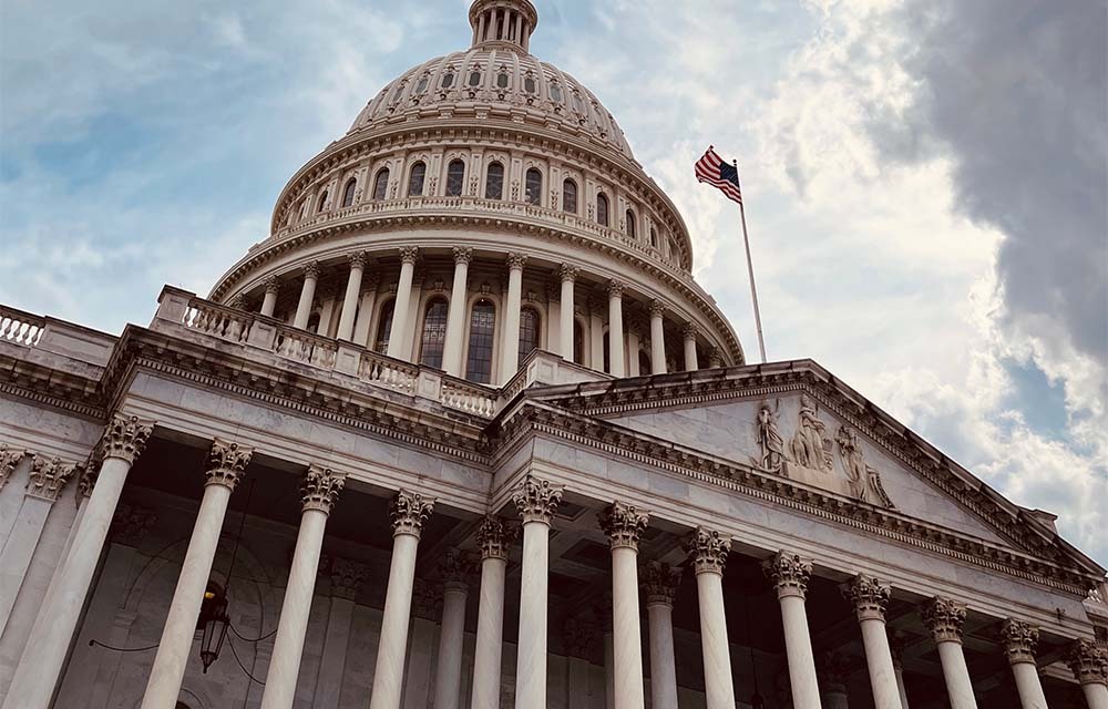 The United States Capital building with the American flag waving in the wind.